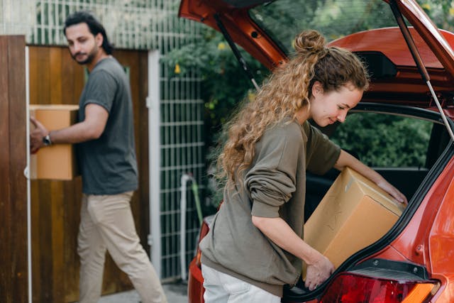 people loading moving boxes into a car